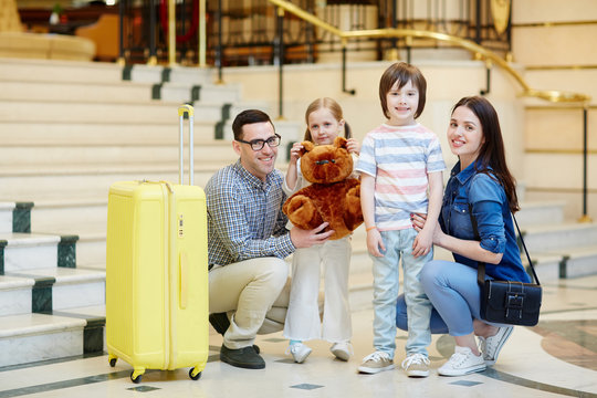 Family of tourists with luggage standing in hotel lounge