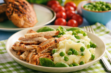 Grilled turkey fillet with mashed potatoes and green peas.