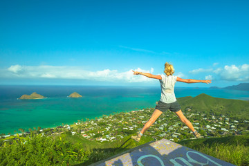 Lanikai Pillbox Hike. Hawaiian hiking enjoying. Joyful carefree hiker jumping. Happy woman celebrates one of most spectacular Oahu hiking trails in Hawaii over Lanikai Beach and Mokulua Islands.