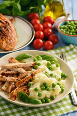 Grilled turkey fillet with mashed potatoes and green peas.