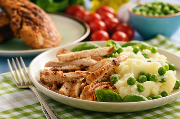 Grilled turkey fillet with mashed potatoes and green peas.