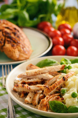 Grilled turkey fillet with mashed potatoes and green peas.