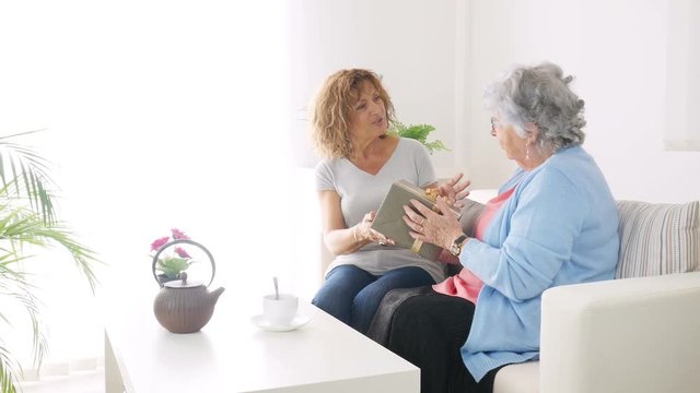 mature woman offering present gift to elderly senior lady for mother's day birthday or anniversary