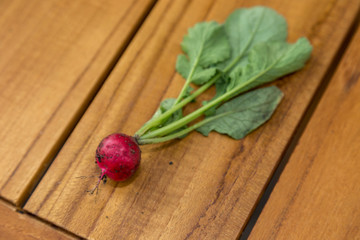 Fresh radish with green leaves on a natural wood table