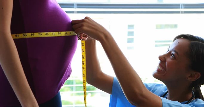 Doctor measuring pregnant womans belly in ward