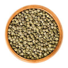 Green pepper in wooden bowl. Dried berries of Piper nigrum are called peppercorns. Made from the unripe drupes of the pepper plant. Spice and seasoning. Isolated macro food photo close up over white.
