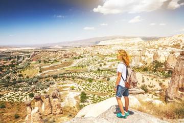 Fototapeta premium A young woman traveler stands on a mountain and admires the view. Turkey, Cappadocia