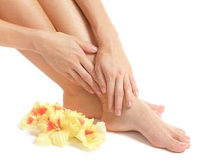 Female legs and hands with flowers on white background