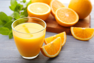 Glass of fresh juice and fruit slices on wooden background
