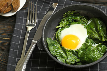Delicious eggs Florentine in frying pan and napkin on wooden kitchen table
