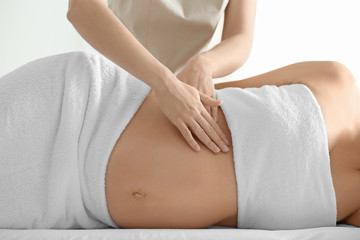 Fototapeta na wymiar Young beautiful pregnant woman having massage in spa salon