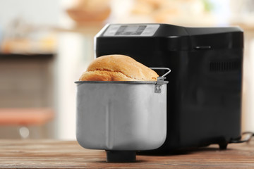 Tasty loaf and bread machine on table