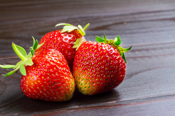 Fresh organic strawberries on dark wooden planks background, close-up view