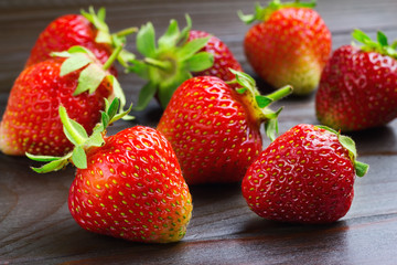 Fresh organic strawberries on dark wooden planks background, close-up view