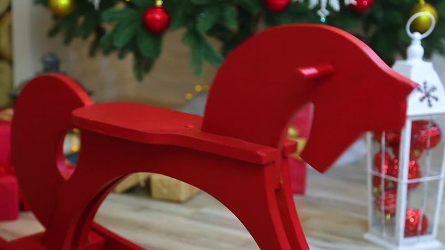 Closeup of red vintage wooden rocking horse in holiday christmas interior. Real time full hd video footage.