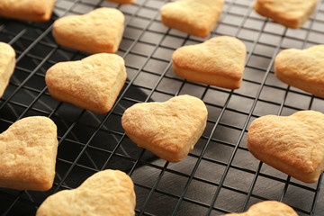 Baking grid with heart shaped butter cookies on table