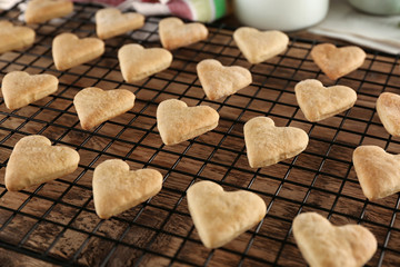 Baking grid with heart shaped butter cookies on table