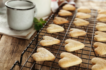 Baking grid with heart shaped butter cookies on table