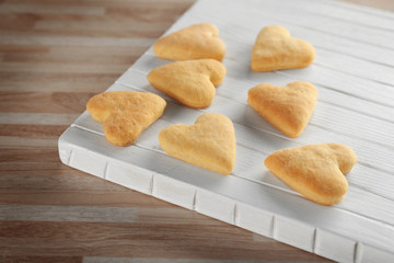Wooden board with heart shaped butter cookies on table