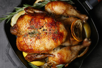 Homemade baked chicken with lemon and rosemary on table