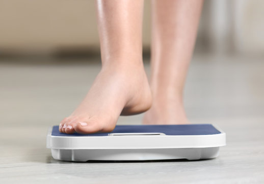 Woman standing on scales on wooden floor. Concept of weight loss