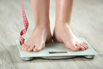Woman standing on scales on wooden floor. Concept of weight loss