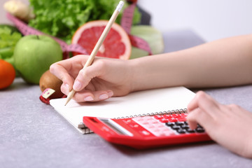 Woman writing a diet plan and calculating calories