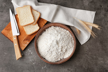 Bowl of wheat flour on dark table, top view