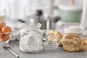 Jar with flour and ingredients for dough in kitchen