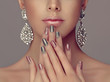Beautiful model girl with pink and gray silver metallic manicure on nails . Fashion makeup and cosmetics . Big silver diamond shine earrings jewelry .