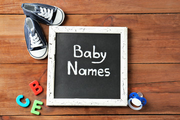 Chalkboard with text BABY NAMES on wooden background