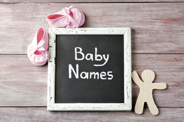 Chalkboard with text BABY NAMES on wooden background