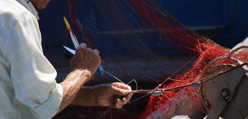 mani di un pescatore al lavoro sulle reti