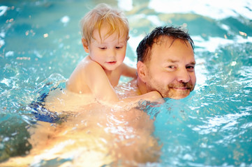 Fototapeta na wymiar Happy little boy with his father in swimming pool