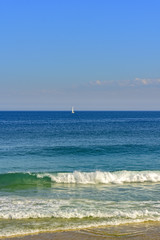 Fototapeta na wymiar Sailboat at horizon line of the blue waters on Ipanema beach at Rio de Janeiro