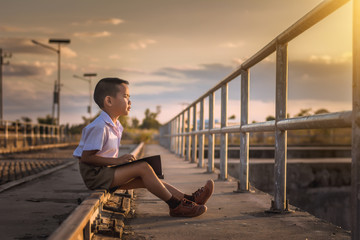 Boy student reading at the bridge at sunset,dream concept.
