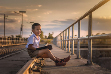 Boy student reading at the bridge at sunset,dream concept.