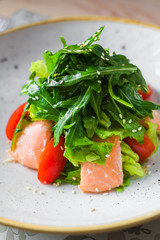 Close-up salad of red fish, arugula, cherry tomatoes, sesame, spices, beautiful trendy dish, restaurant, bright, tasty, colorful