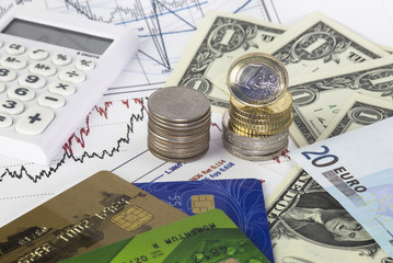 Charts with retail market prices, Heap of  quarter dollars, heap of euro coins, one us dollar bills, twenty euro bill, calculator and credit cards on the diagram.  Concept of retail business trading.