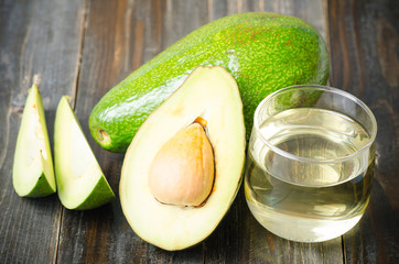 Half of avocado fruit and oil on wooden background,Healthy food