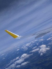 Naklejka na ściany i meble Airplane wing. Flight with blue sky and clouds background