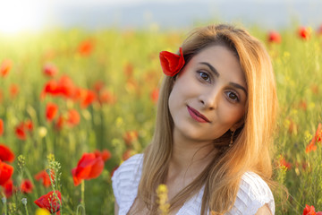 Portrait of blonde woman standing on field of poppies
