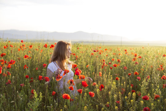 Woman in white dress standing in field of poppies