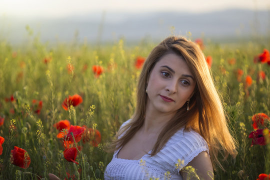 Portrait of blonde woman in field of poppies