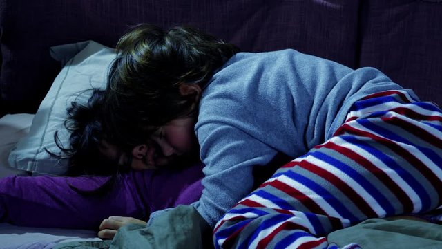 Boy hugging mother at night in bed while she is sleeping