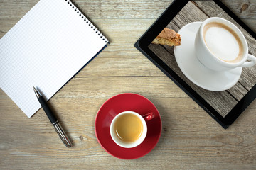 Tasse Cappuccino im Tablet Computer und Block mit Kugelschreiber