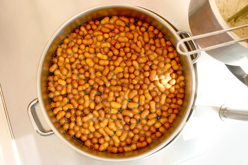 Sweet mini donuts frying in oil. Pot with mini donuts top view.