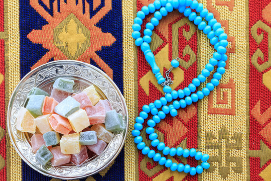 Turkish delights and blue rosary on traditional turkish carpet