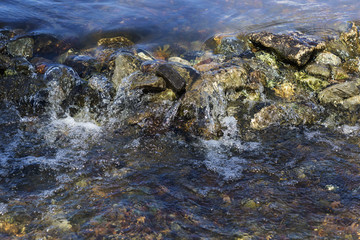 Fototapeta na wymiar Stream flowing over stones rough rocks