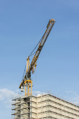 Fototapeta premium Construction crane and top of the building with scaffolding.